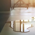 Water leak on a floor reflecting light, indicating potential plumbing issues related to leak detection services by Chris Wilson Plumbing & Heating Repairs Inc.