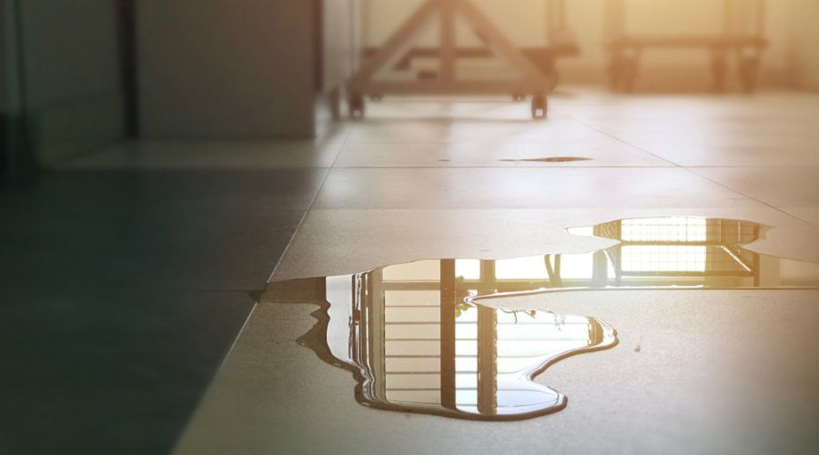 Water pooling on tiled floor, highlighting plumbing leak issue relevant to preventing high water bills and property damage.